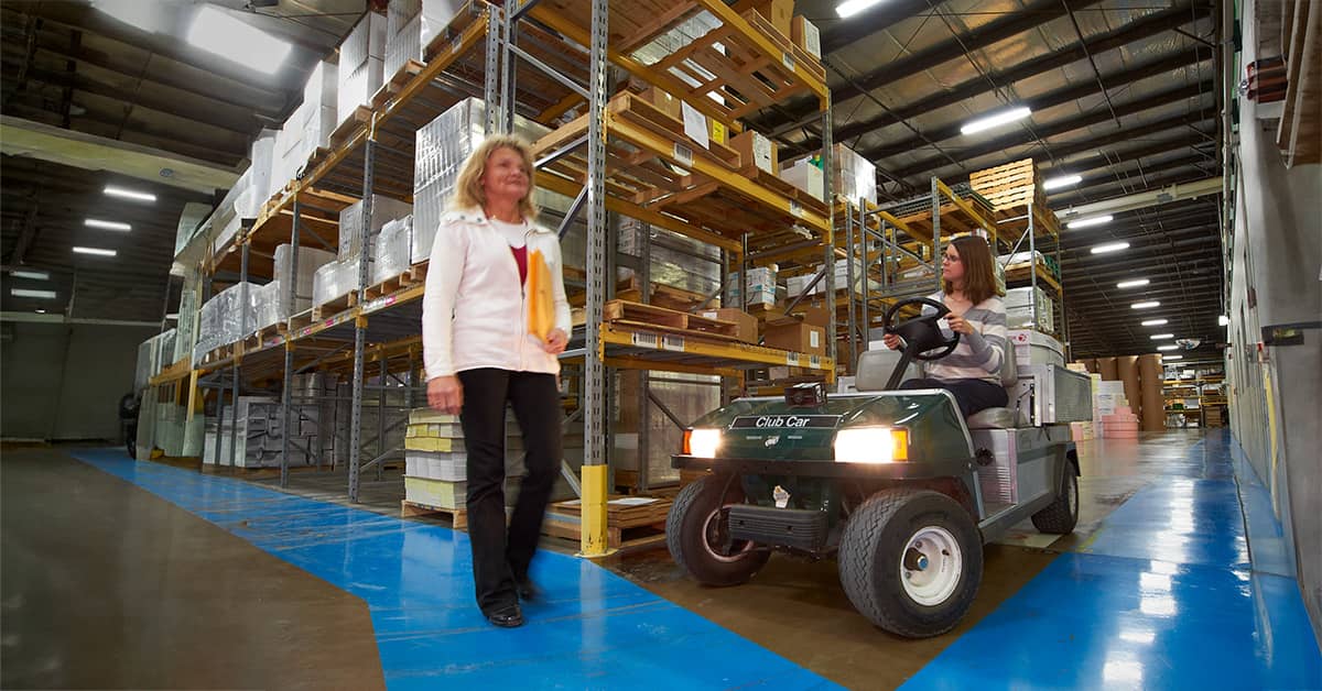 Golf Cart in warehouse stopped for pedestrian to cross